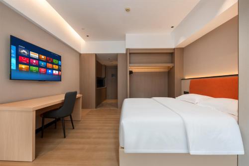 a hotel room with a bed and a desk and a tv at Mido International Hotel in Guangzhou
