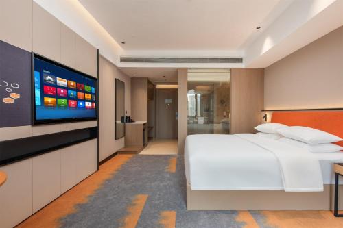 a bedroom with a white bed and a flat screen tv at Mido International Hotel in Guangzhou