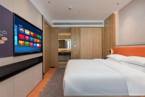 a bedroom with a white bed and a flat screen tv at Mido International Hotel in Guangzhou