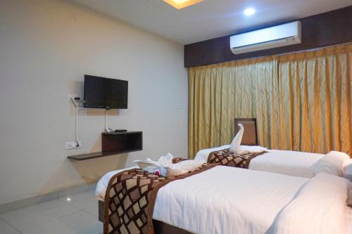 a hotel room with two beds and a television at Hotel Green Park Elite in Kākināda