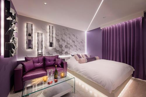 a purple bedroom with a bed and a couch at ホテルLuce Regaloｰルーチェレガーロ in Rifu