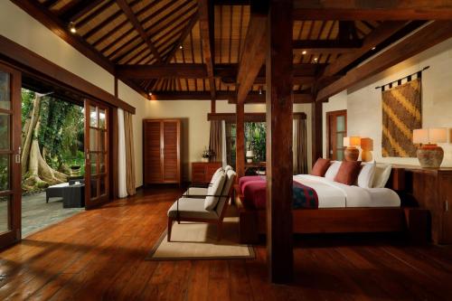 a bedroom with a bed and a chair in a room at Villa Tirtadari by Nakula in Kerobokan