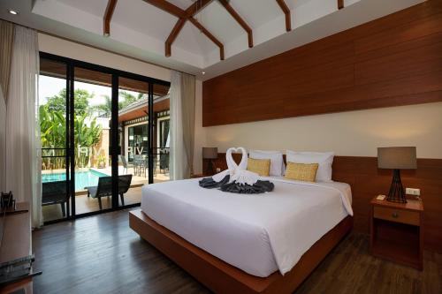 ein Schlafzimmer mit einem großen weißen Bett und einem Pool in der Unterkunft Orchid Villa - 3 Bedrooms Pool Villa - Rawai beach in Rawai Beach