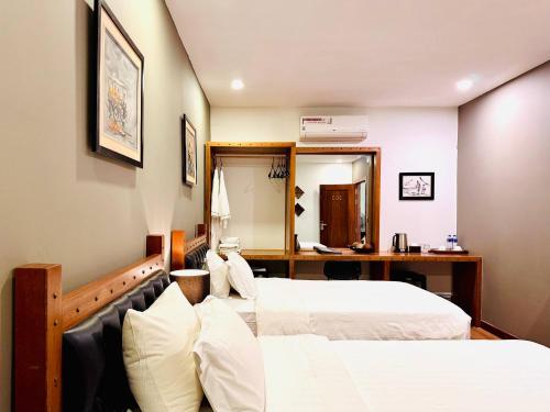a hotel room with two beds and a desk at Lavanya Boutique Hotel in Phnom Penh