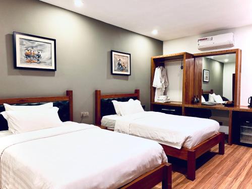 a bedroom with two beds and a desk with a mirror at Lavanya Boutique Hotel in Phnom Penh