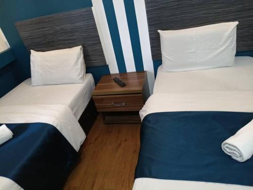 a room with two beds and a nightstand between them at V Hotel Titiwangsa in Kuala Lumpur