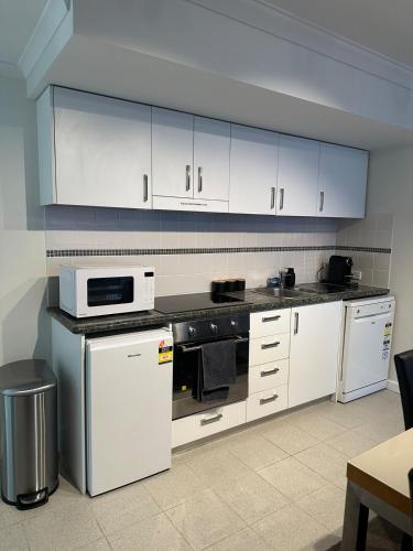 a kitchen with white cabinets and a stove top oven at City Lights Retreats - 2 Bedroom, 1 Bathroom in Perth