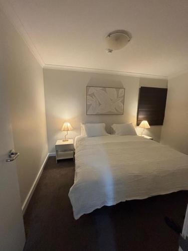 a bedroom with a large white bed with two lamps at City Lights Retreats - 2 Bedroom, 1 Bathroom in Perth