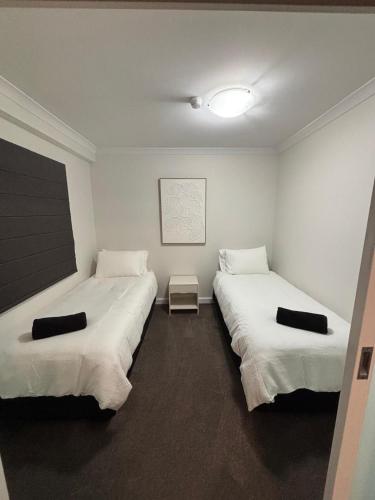 two beds in a room with white walls at City Lights Retreats - 2 Bedroom, 1 Bathroom in Perth
