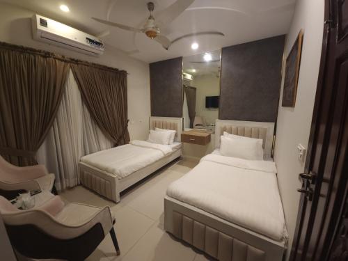 a hotel room with two beds and a chair at Aspire Lodge, G11 Islamabad - A Family Guest House & Hotel in Islamabad