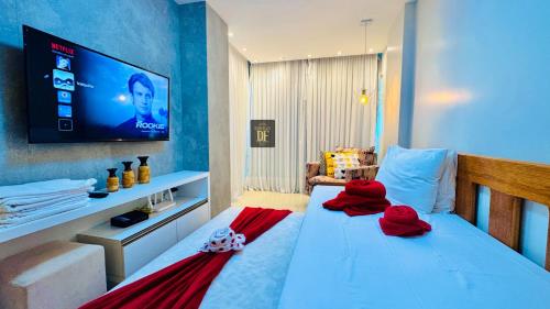 a bedroom with a bed with red pillows and a flat screen tv at Vg Fun by Diego Flats in Fortaleza