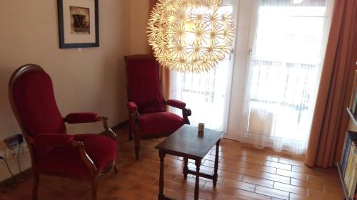 a living room with chairs and a table and a chandelier at Au P'tit Bonheur in Cheseaux