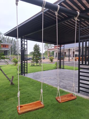 two swings on the grass in a park at บ้านน้ำผึ้งโฮมสเตย์ in Suan Phung