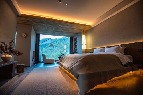a bedroom with a large bed and a large window at Siguniang Mountain Star Moon Cliff Hotel in Mount Siguniang