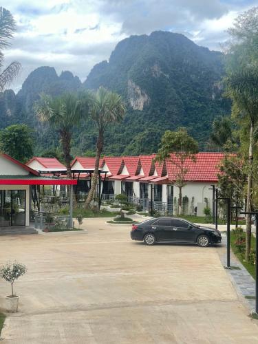a black car parked in a parking lot with mountains in the background at Ruby Mountain View Resort Vang-vieng in Vang Vieng