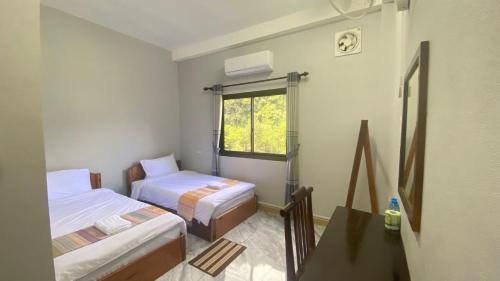 a small room with two beds and a window at Houngvilai Guesthouse in Ban Sôphoun