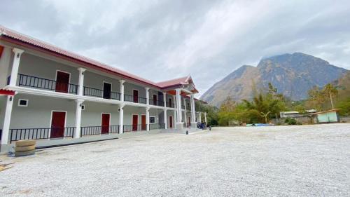 a building with red doors and mountains in the background at Houngvilai Guesthouse in Ban Sôphoun