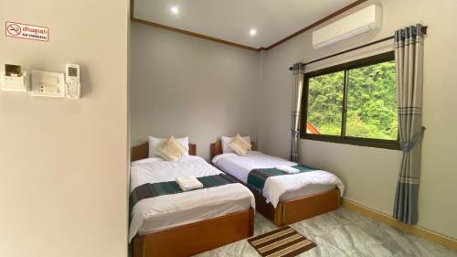 two beds in a room with a window at Houngvilai Guesthouse in Ban Sôphoun