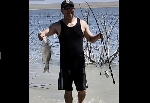 a man standing on the beach holding a fish at Kiowa RV Park in Eads