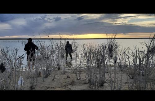 two people are standing on a beach near the water at Kiowa RV Park in Eads