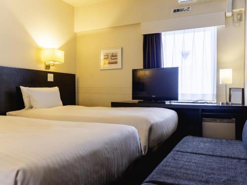 a hotel room with two beds and a flat screen tv at KOKO HOTEL Yokohama Tsurumi in Yokohama