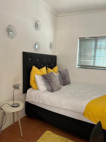 a bedroom with a bed with yellow and gray pillows at Mekenificent Stays in Windhoek