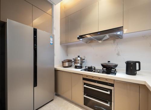 a kitchen with a refrigerator and a stove top oven at Sanya Haitang Bay Muyu Time Seaview Apartment in Sanya