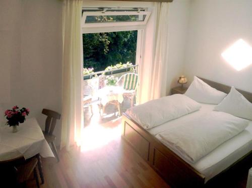 1 Schlafzimmer mit einem Bett und einem Balkon mit einem Tisch in der Unterkunft Hotel Garni Seerösl am Wörthersee , Kärnten in Krumpendorf am Wörthersee