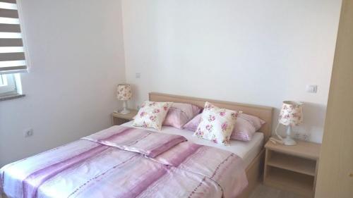 1 dormitorio con 1 cama con sábanas y almohadas rosas en Villa Palas Apartments 2, en Rogoznica