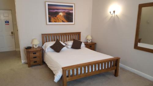 a bedroom with a bed and two night stands and a mirror at Nant Ddu Lodge Hotel & Spa in Merthyr Tydfil