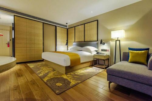 a bedroom with a large bed and a couch at Echarm Hotel Anshun High-speed Railway Station Jichang Road in Anshun