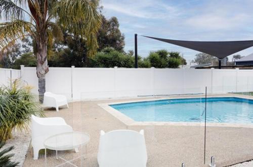 a swimming pool with white chairs and a white fence at Yarrawonga walk everywhere in Yarrawonga