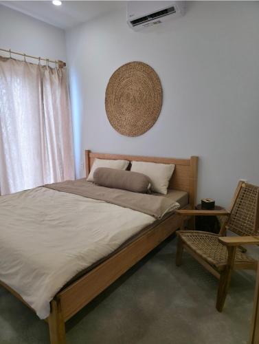 a bedroom with a large bed and a chair at Kihu Home Phan Thiet in Bình Sum