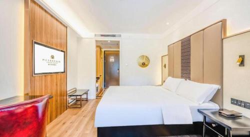 a bedroom with a large white bed and a desk at Jinjiang Metropolo Haikou East High Speed Railway Station Normal University in Haikou