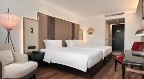 a bedroom with a large white bed and a couch at Jinjiang Metropolo Haikou East High Speed Railway Station Normal University in Haikou
