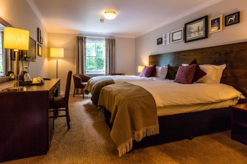 a hotel room with two beds and a desk at Greyhound Hotel in Sutton
