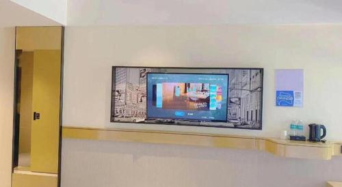 a flat screen tv on a wall in a room at City Comfort Inn Kunming High Speed Railway South Station Yongxin Harvard in Kunming