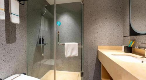 a bathroom with a glass shower and a sink at City Comfort Inn Shiyan Wudang Mountain in Danjiangkou