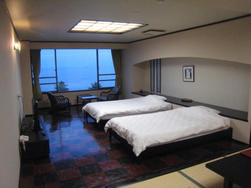 a hotel room with two beds and a table and chairs at Utsumionsen Ichizu in Minamichita