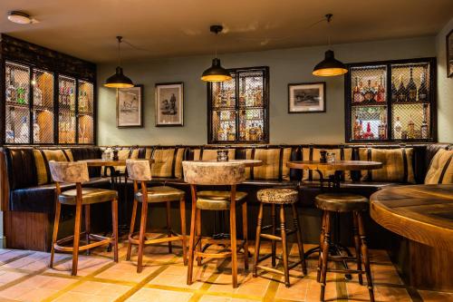 a bar with wooden stools and stained glass windows at Greyhound Hotel in Sutton