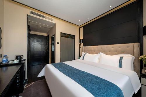 a bedroom with a large bed with a large headboard at Xana Hotelle Wuxi Railway Station Zhongshan Road in Wuxi