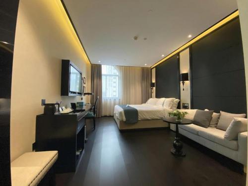 a hotel room with a bed and a couch at Xana Hotelle Wuxi Railway Station Zhongshan Road in Wuxi