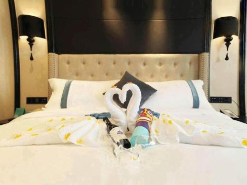 a bed with two white swans on it at Xana Hotelle Wuxi Railway Station Zhongshan Road in Wuxi