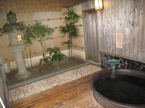 a bath tub with a fountain in a room with plants at Utsumionsen Ichizu in Minamichita