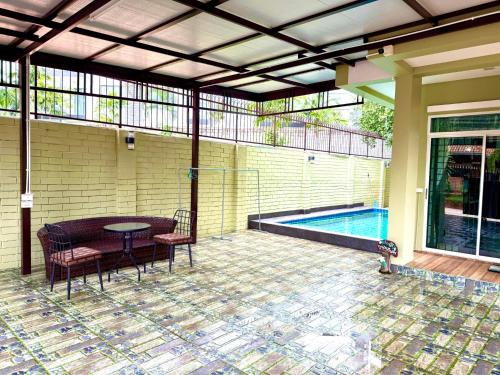 パタヤ・サウスにあるWarisa Happy Pool Villa Near Pattaya Beachのテーブルと椅子とプールのあるパティオ
