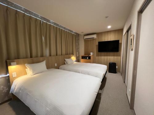 a hotel room with two beds and a flat screen tv at UDON na HOTEL 琴平 in Kotohira