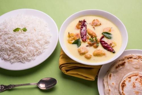 a plate of food with rice and a bowl of soup at Hotel O Sky Inn in Jaipur