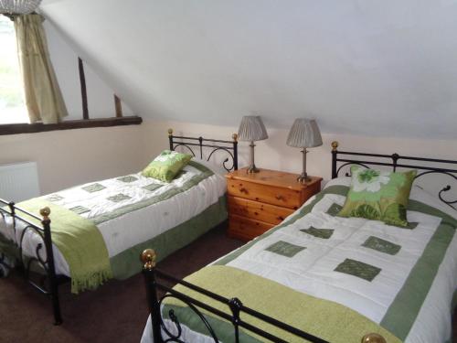 a bedroom with two beds and a wooden dresser at Minsmere Cottage in Yoxford