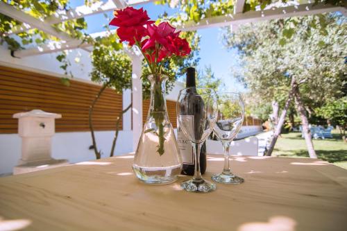 a vase with a red rose and two glasses on a table at Jaz Garden Residence in Budva