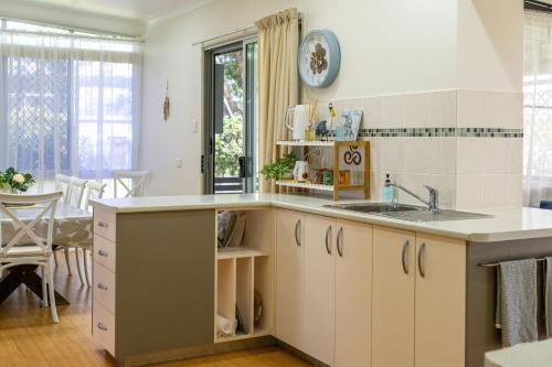 a kitchen with white cabinets and a sink at The Lazy Pelican in Tin Can Bay